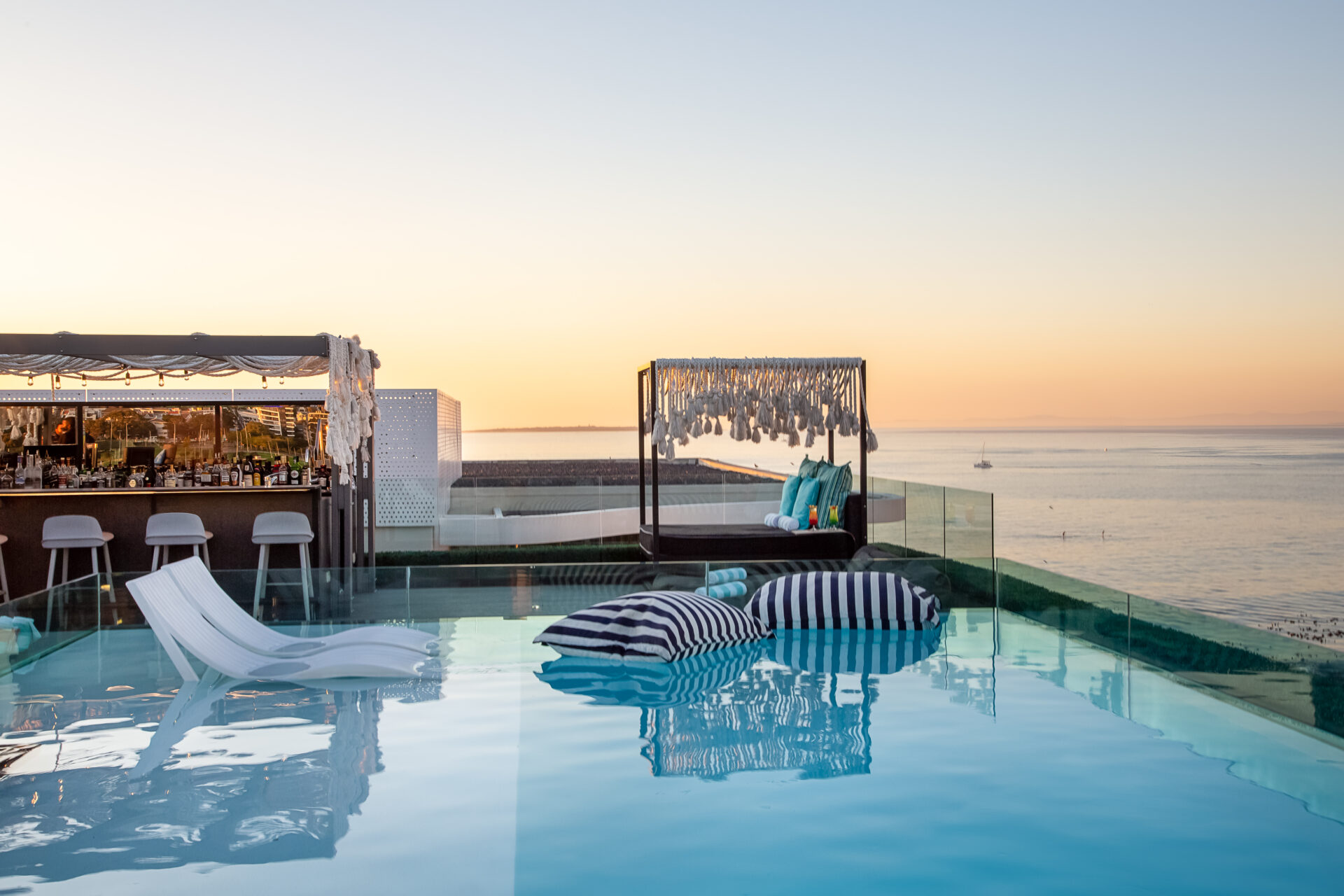 A rooftop deck with a luxurious bar, a lounger, a pool and panoramic views of the sea