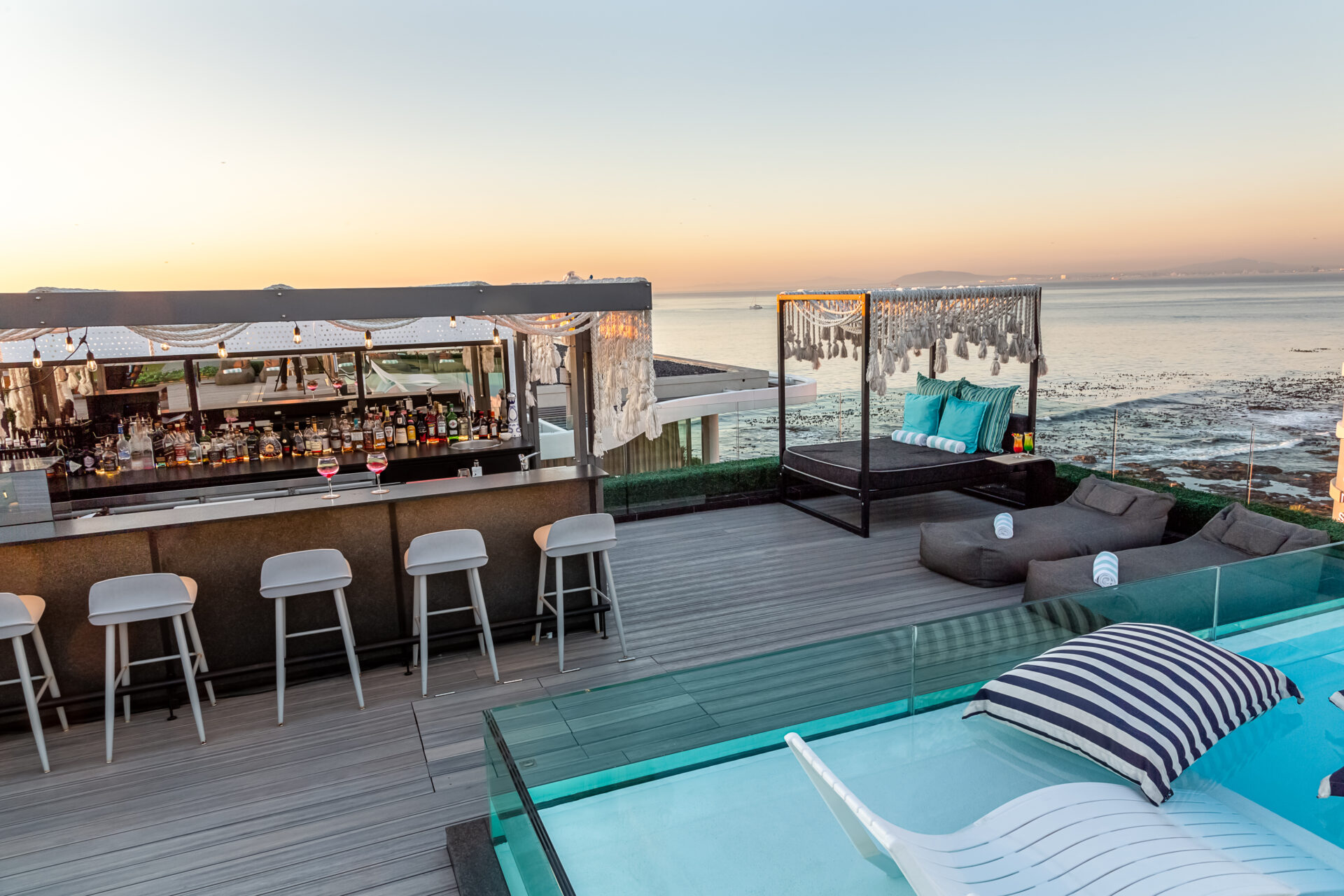 A rooftop deck with a luxurious bar, a lounger, a pool and panoramic views of the sea