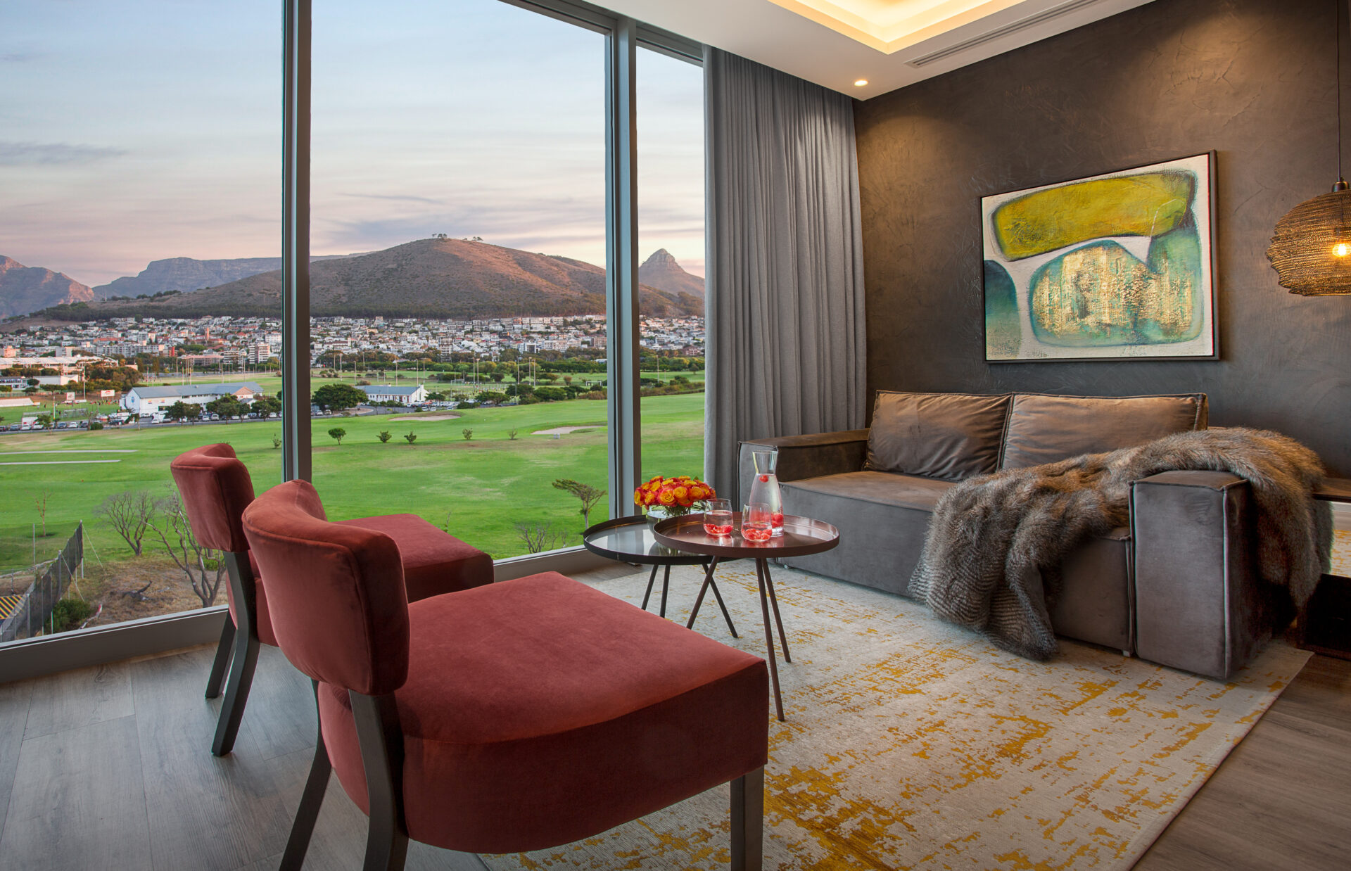 A luxurious lounge with floor to ceiling windows looking onto a golf course, residential buildings and mountains