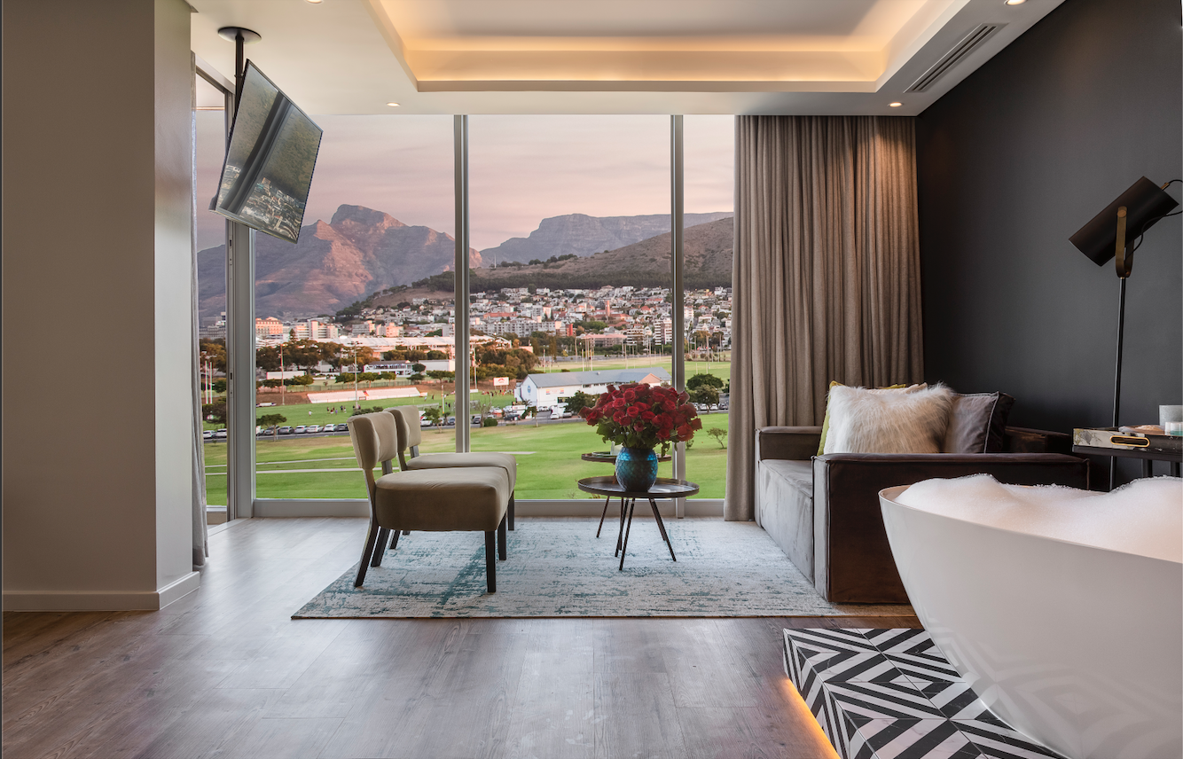 A luxurious lounge area with seating and floor to ceiling windows looking onto a golf course, residential buildings and mountains