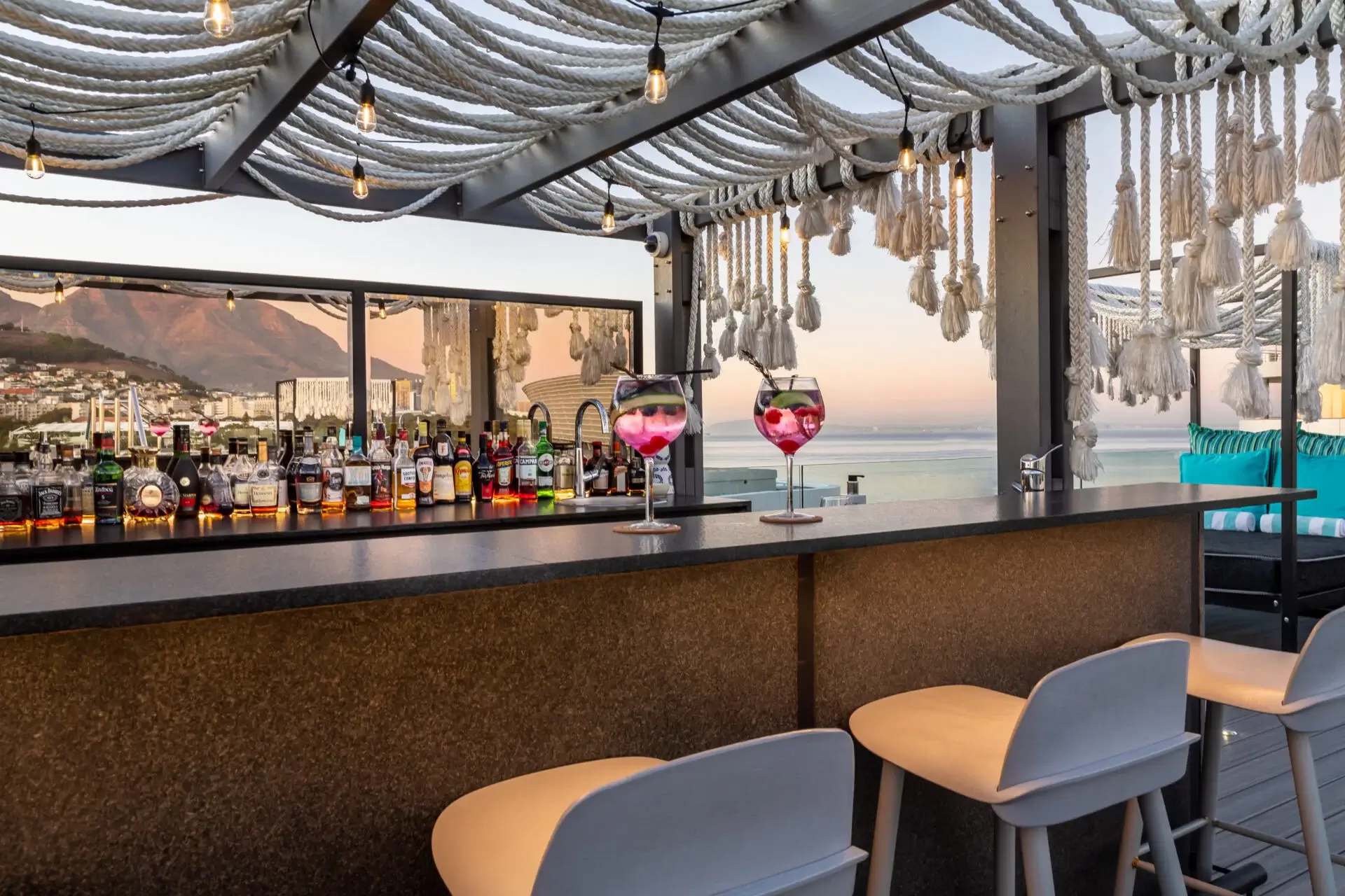 A rooftop luxurious bar, a lounger with two cocktail glasses