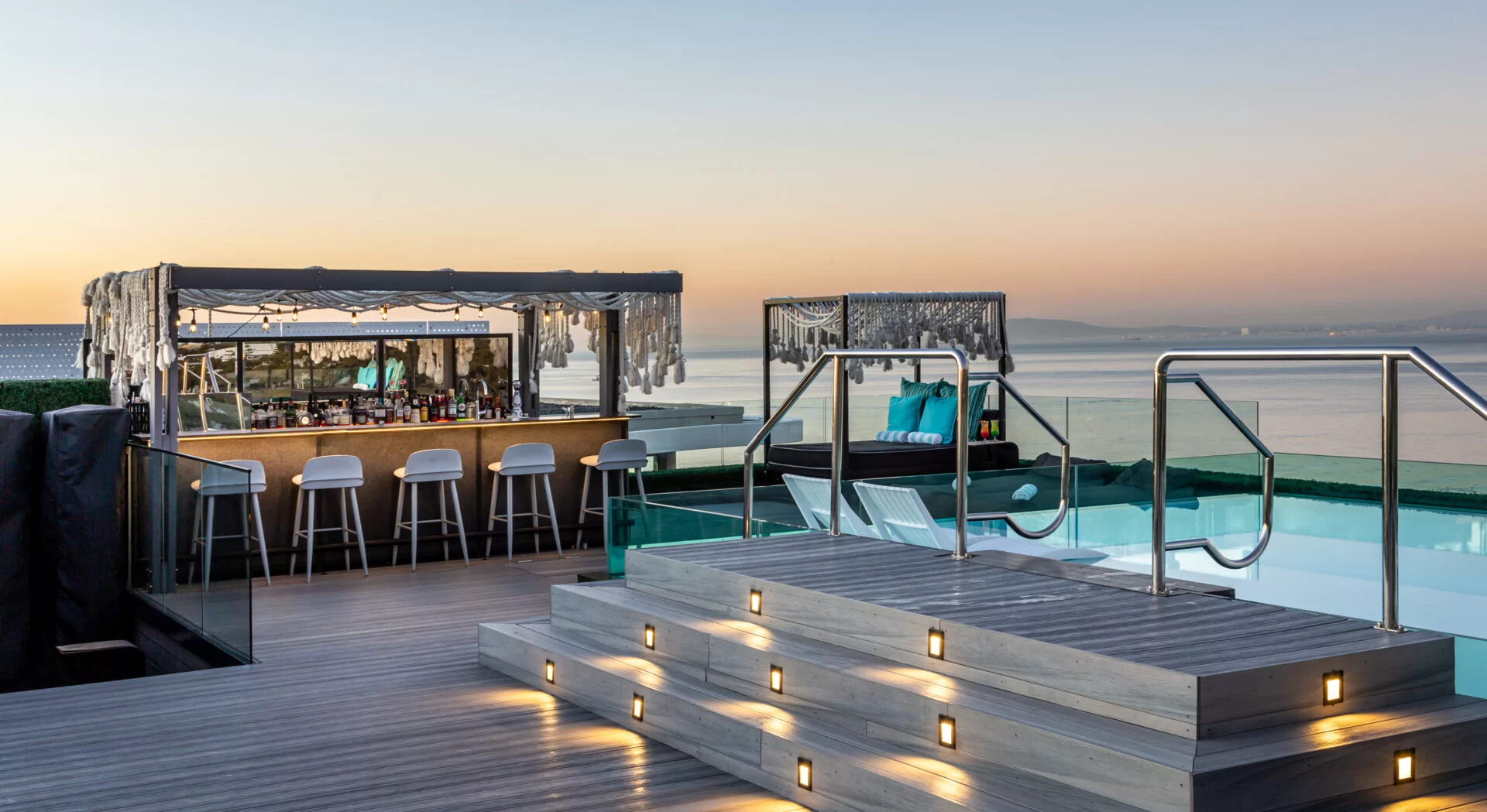 A rooftop deck with a luxurious bar, a lounger, a pool and panoramic views of the sea